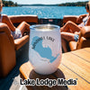 A white stainless steel wine tumbler with a blue map of Sandhill Lake, Wisconsin, sits on a wooden table on a boat, with two women relaxing in the background.