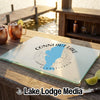 A rectangular glass cutting board featuring a blue map of Conneaut Lake, Pennsylvania, rests on a wooden table outdoors.