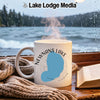 White mug with "Newnans Lake Florida" design on a wooden surface with a book and scarf.