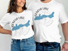 White t-shirts feature a blue Geneva Lake silhouette over a compass design with text.