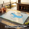 A tempered glass cutting board featuring a blue map of Harlan County Lake, Nebraska, resting on an outdoor wooden table.