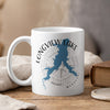 White mug with blue Longview Lake shape and compass on rustic wooden surface.