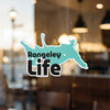 Rangeley Life text on a teal shaped sticker adhered to a glass surface.