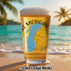 Beer glass with Michigan map and compass on beach with palm trees.