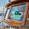Turquoise "Ossipee Life" sticker on a wooden boat window, "Lake Lodge Media" text below.