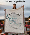 Man holding a woven blanket with East Lynn Lake map and compass design.