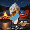 Glass of beverage with whipped cream, s'mores ingredients, campfire, and lake scene.