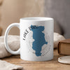 White mug with Lake Piru California map and compass design, steaming.