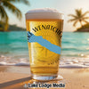 Glass of beer with "Lake Wenatchee Washington" text and compass design on beach.