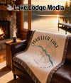 Woven throw blanket with Wheeler Lake Alabama compass design on leather couch.