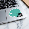 Teal sticker with "Crater Life" text on a laptop keyboard.