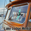 Canadice Life logo sticker on a wooden boat with Lake Lodge Media text.