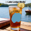 Iced tea in a glass with a lemon slice on a table by a lake.