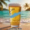 Glass of beer with "Lake Erie" and compass design on a beach.
