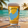 Beer glass with "Rose Canyon Lake" and Arizona map graphic on a beach.
