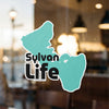 Teal Sylvan Life sticker with text and logo on a window.