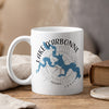 White mug with blue map of Lake D'Arbonne and compass on wood surface.
