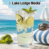 Tall glass with lime drink and compass design, beach scene.