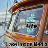 Turquoise Disharoon Life sticker on a wooden boat window, text "Lake Lodge Media".
