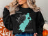 Black sweatshirt with a teal outline of Lake Quaboag, Massachusetts and compass rose.