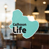 Teal sticker with text Calhoun Life on a glass surface.