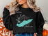 Black crewneck sweatshirt with turquoise Lake Erie map and compass graphic.