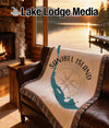 Woven blanket with Sanibel Island map and compass design on leather couch.