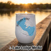 A white wine tumbler featuring a blue Sylvan Lake map graphic sits on a wooden dock.