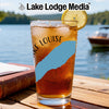 Glass of iced tea with lemon and a compass design, on a table by a lake.