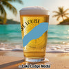 Glass of beer with "KE LOUISE" text and compass design on a beach.