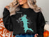 Black sweatshirt with a teal Lynx Lake, Arizona map design and compass.