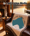 Cream woven blanket with Little Turtle Lake, Minnesota design on a leather couch.