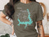 Olive t-shirt with teal map graphic of Lake Thunderbird, Oklahoma and compass rose.