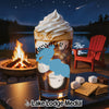 Iced coffee topped with whipped cream beside s'mores ingredients at a campsite.