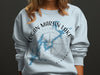 Light blue crewneck sweatshirt with Logan Martin Lake map and compass design.