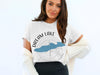 White t-shirt with "DREAM LAKE" text and a blue lake outline over a compass.