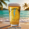 Beer glass with "Lake Champlain" and compass design on a beach.