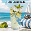 Tall glass of lemonade with limes and mint on a beach with a sailboat.
