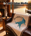 Fringed blanket with Benbrook Lake map and compass design on a leather couch.