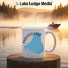 Mug with Emerald Lake map and compass design in front of a misty lake scene.
