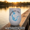 White stemless wine tumbler featuring a Broadway Lake map and compass graphic, resting on a wooden dock outdoors at sunset.