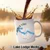 White mug with "Alder Lake" text, map, and compass graphic, coffee pouring.