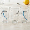 Three clear glasses featuring "Cayuga Lake New York" with a blue lake silhouette and compass graphic.