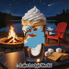 Glass with layered drink and whipped cream on a table with s'mores ingredients.