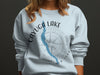 Light blue sweatshirt with an illustration of Cayuga Lake, NY and a compass.