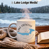 White mug with "Lake Crescent Washington" graphic and compass on wooden surface.