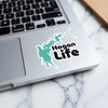 Turquoise Hogan Life sticker on a laptop keyboard with white marble surface.