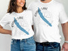 White t-shirts with Otisco Lake graphics and compass rose design.