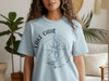 Light blue t-shirt with Lake Oahe compass design and "North Dakota" text.