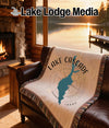A throw blanket with a map of Lake Cascade, Idaho, is draped over a leather couch.
